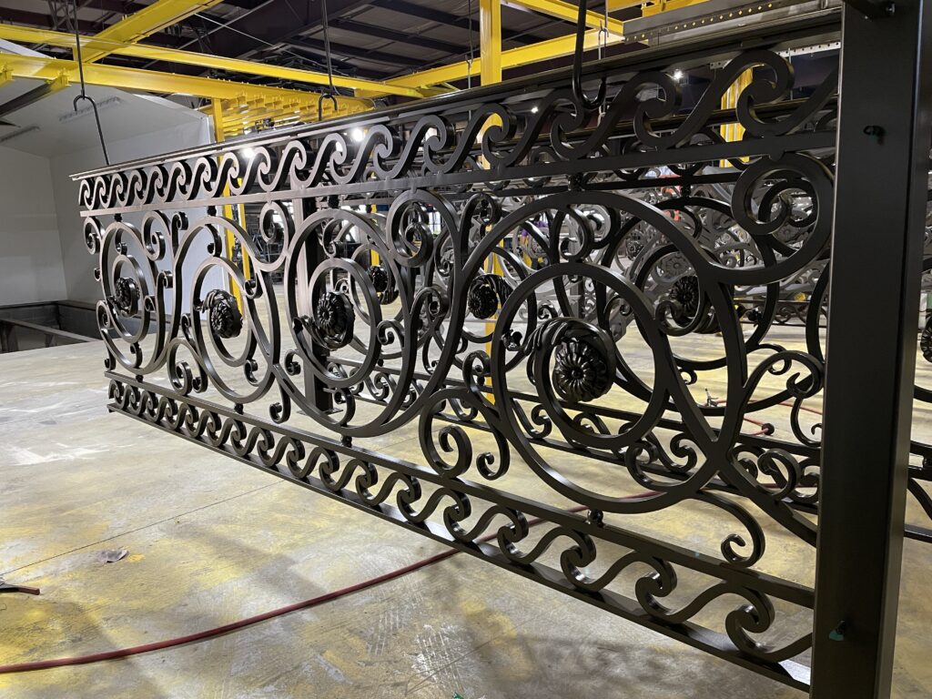 close up of intricate iron work with spirals, flowers, and wave designs with black powder coating